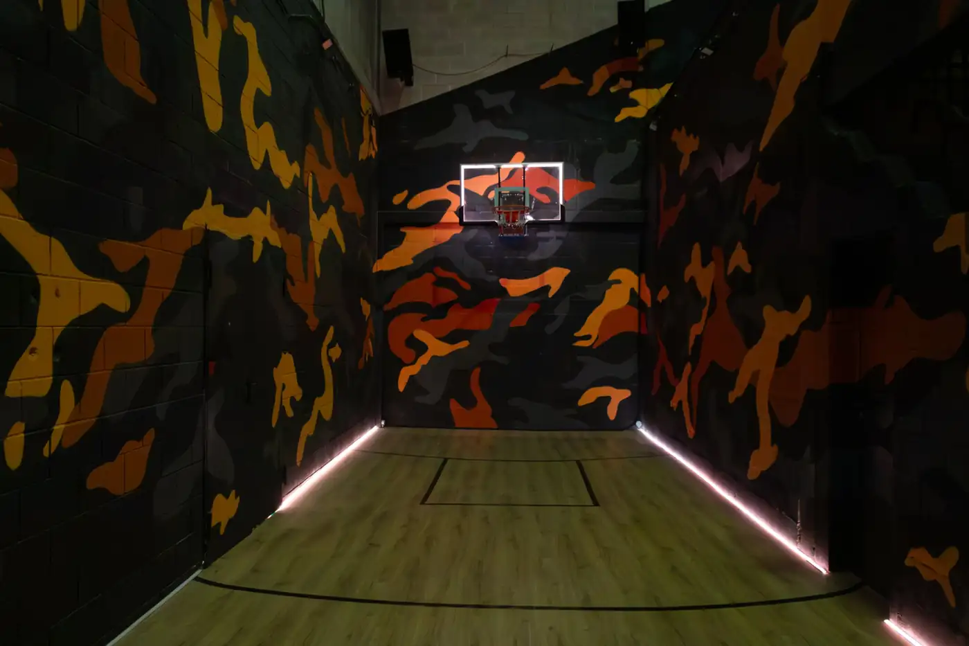 Cancha de básquet de Korner con la canasta iluminada y las paredes de camuflaje